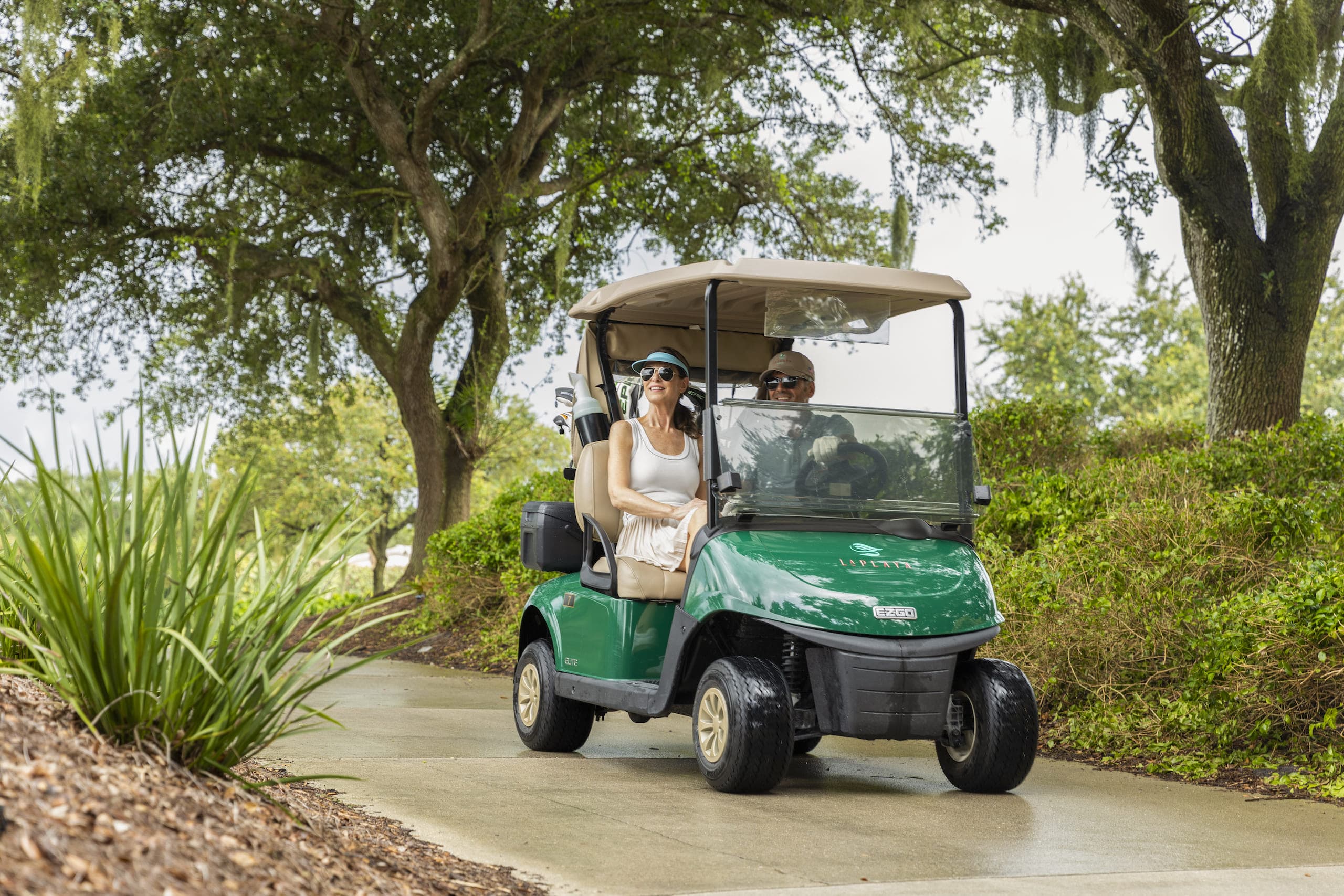 A couple in a golf cart on a golf course path